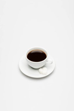 Bir fincan taze kahve ve çay tabağında şeker.