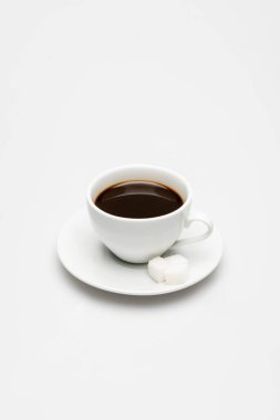 Bir fincan kahve ve çay tabağının üstüne beyaz şeker.