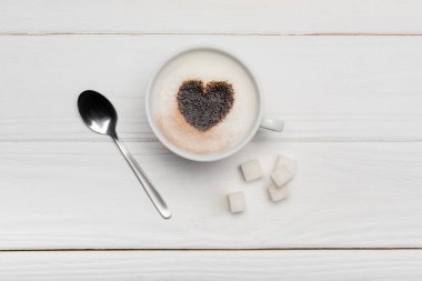 top view of cup with cappuccino near spoon and sugar cubes on white wooden background   clipart