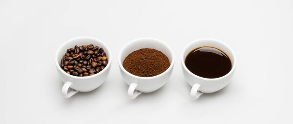 чашки с приготовленным кофе и молотый кофе возле бобов на белом, баннер