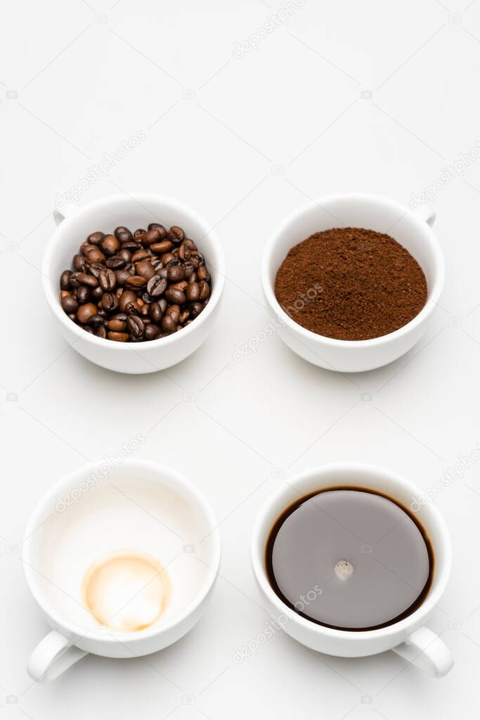 top view of prepared americano near ground coffee and beans in cups on white
