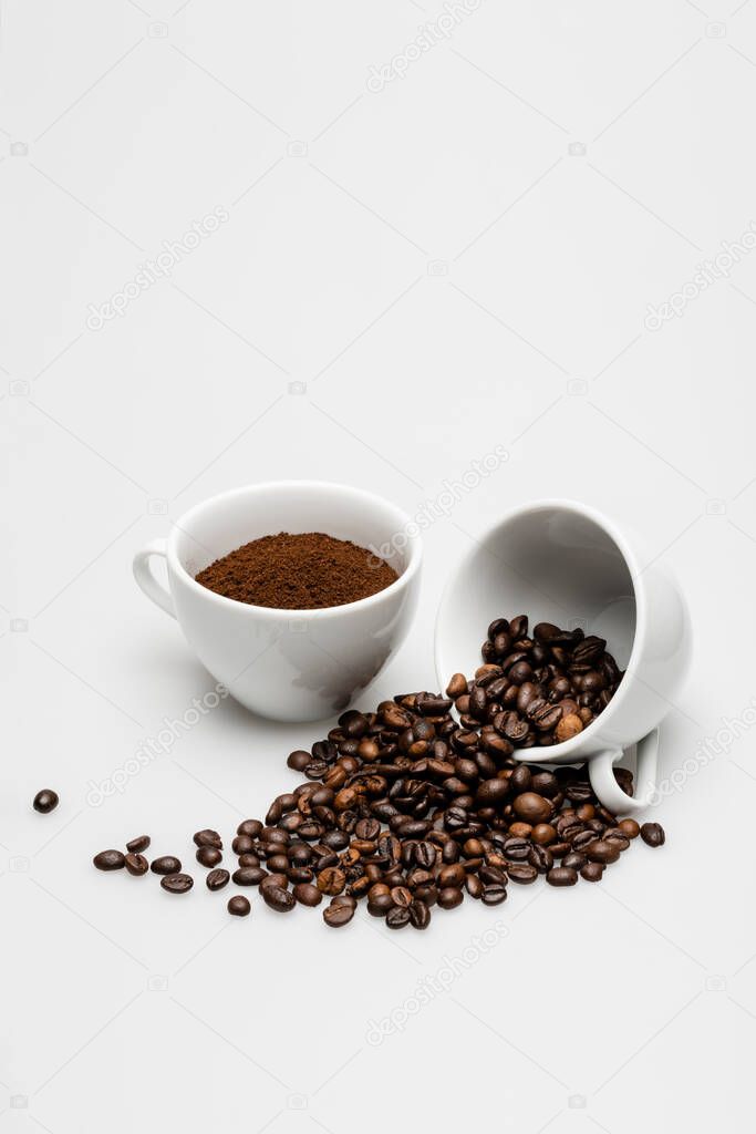 beans and ground coffee in mugs on white