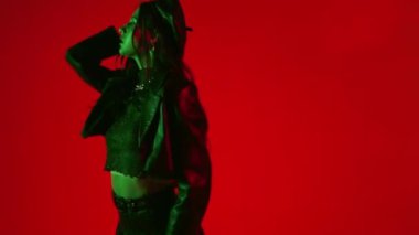 Kırmızı arka planda dans eden modaya uygun kadınların yavaş çekimleri. 