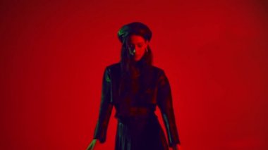 Siyah elbiseli bir kadının kırmızı arka planda dans etmesi. 