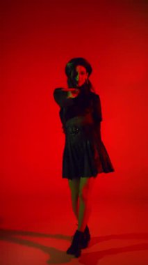 Kırmızı arka planda dans eden etekli ve bereli bir kadın. 