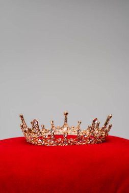 golden royal crown on red velvet cushion isolated on grey clipart