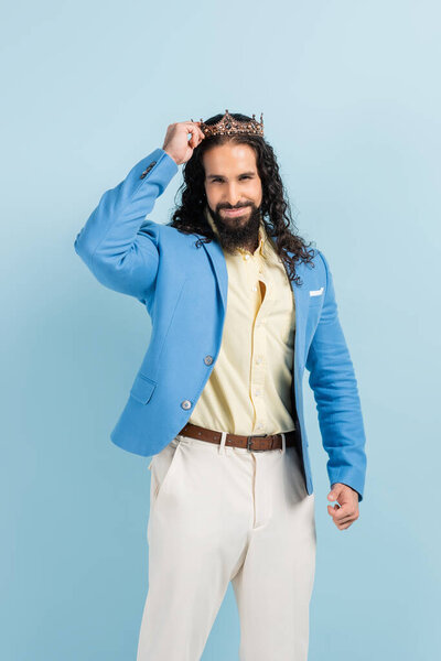 счастливый латиноамериканец регулируя корону изолированы на синий