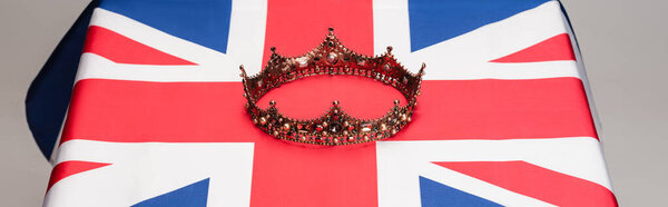 golden royal crown on british flag isolated on grey, banner