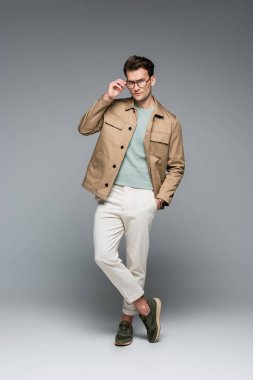 Modayı takip eden şık kıyafetli bir adam. Gri üzerinde el ele poz veriyor.