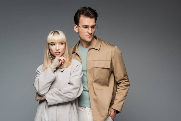 модные модели, позирующие изолированно на сером