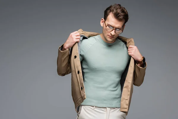 Hombre Moda Gafas Ajustando Chaqueta Mientras Posando Aislado Gris — Foto de Stock