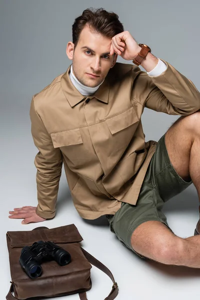 Trendy Traveler Shorts Jacket Sitting Leather Backpack Binoculars Grey — Stock Photo, Image