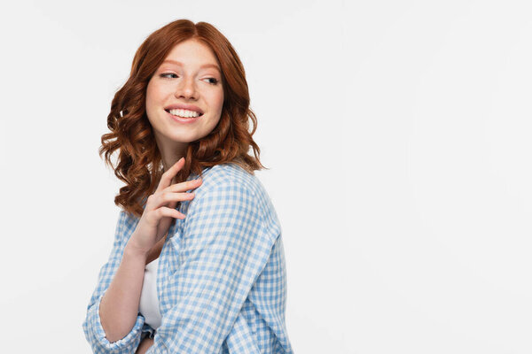 happy redhead young woman in blue checkered shirt looking away isolated on white