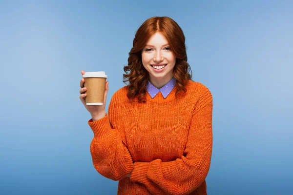 穿着橙色毛衣的红头发女人 手里拿着咖啡 孤零零地躺在蓝色上 — 图库照片