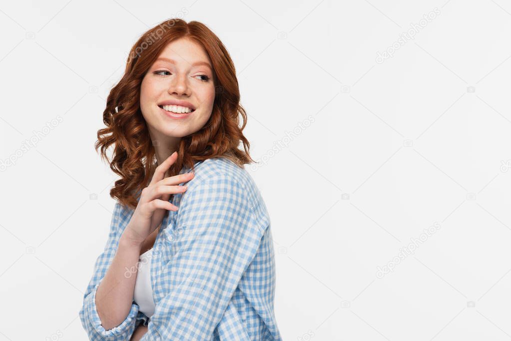 happy redhead young woman in blue checkered shirt looking away isolated on white