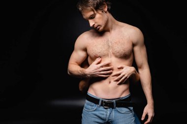 Tutkulu kadın tişörtsüz ve kaslı adama sarılıyor.