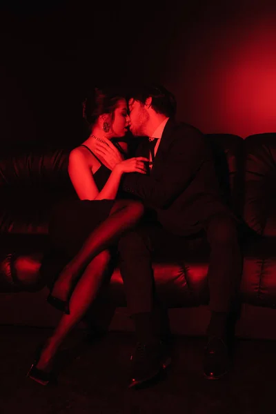 Czerwone Oświetlenie Sexy Para Całowanie Czarnej Skórzanej Kanapie — Zdjęcie stockowe