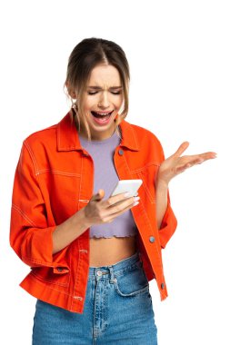 Kırpılmış bluz ve turuncu gömlekli hoşnutsuz genç bir kadın akıllı telefon kullanıyor ve beyaz üzerine izole edilmiş el kol hareketi yapıyor.