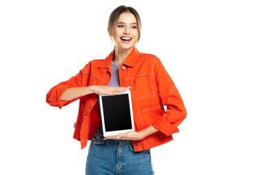 Turuncu gömlekli, kot pantolonlu, elinde beyaz ekranlı dijital tablet tutan mutlu genç bir kadın.