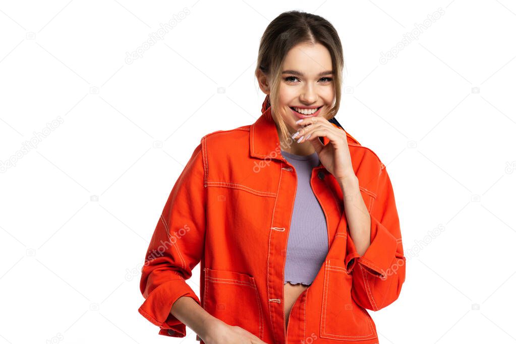 positive young woman in crop top and orange shirt smiling isolated on white 