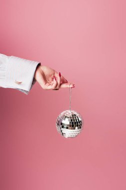Pembe üzerinde disko topu tutan genç bir kadın görüntüsü. 
