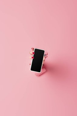 Pembe arka planda delikli, elinde boş ekran olan akıllı telefon görüntüsü. 