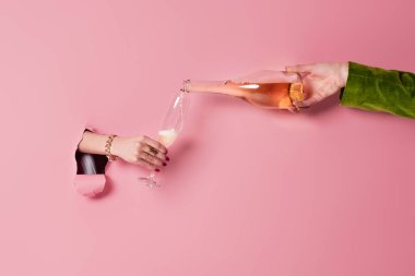 Cropped view of man pouring champagne near woman with glass and pink background with hole  clipart