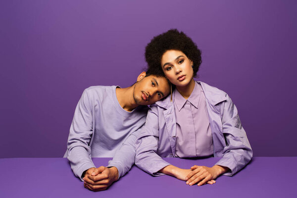 Африканский американец, опирающийся на кудрявую женщину, изолированную от фиолетового 