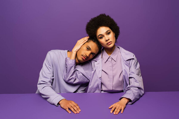 Африканский американец, опирающийся на кудрявую молодую женщину, изолированную от пурпура 