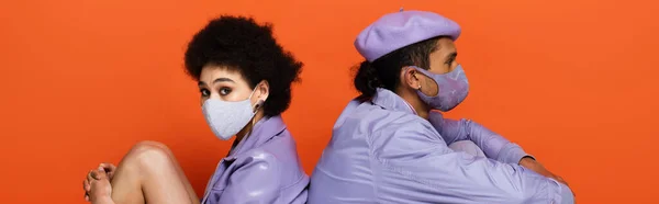Trendy African American Couple Protective Masks Sitting Isolated Orange Banner — Stock Photo, Image
