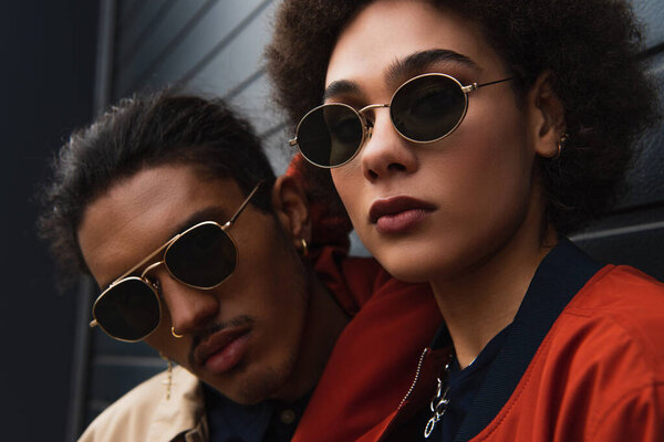 close up of young african american man posing with stylish woman in sunglasses outside 