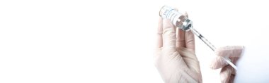Doktorun elinde koronavirüs aşısı ve beyaz pankarta izole edilmiş şırınga tutarken görüntüsü. 