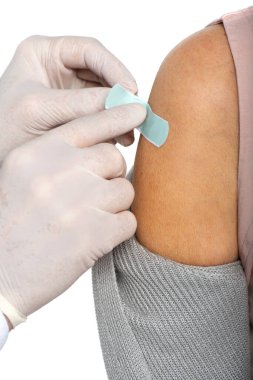Lateks eldivenli doktorun, beyaz üzerine izole edilmiş yaşlı bir kadının koluna yapıştırıcı sürerken çekilmiş görüntüsü. 