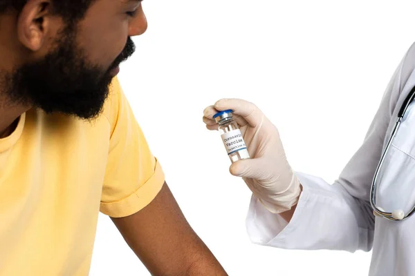 戴乳胶手套的医生拿着装有疫苗的罐子 靠近非洲裔美国人 在白种人身上分离 — 图库照片