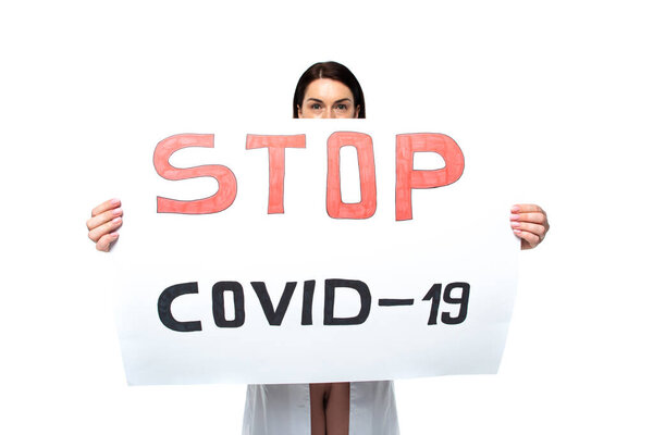 Placard with stop covid-2019 lettering in hands of doctor isolated on white 