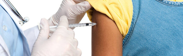 Cropped view of african american child near doctor in latex gloves holding syringe isolated on white, banner 