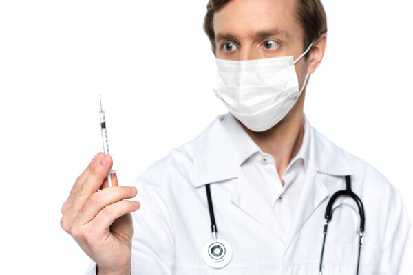 Syringe with vaccine in hand of doctor in medical mask on blurred background isolated on white 