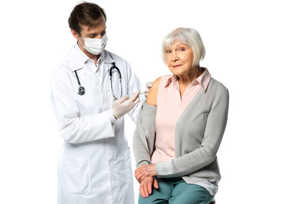 Senior patient looking at camera while doctor doing vaccine injection isolated on white 