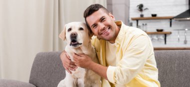 Labrador 'u kucaklayan neşeli adam kameraya, afişe bakarken