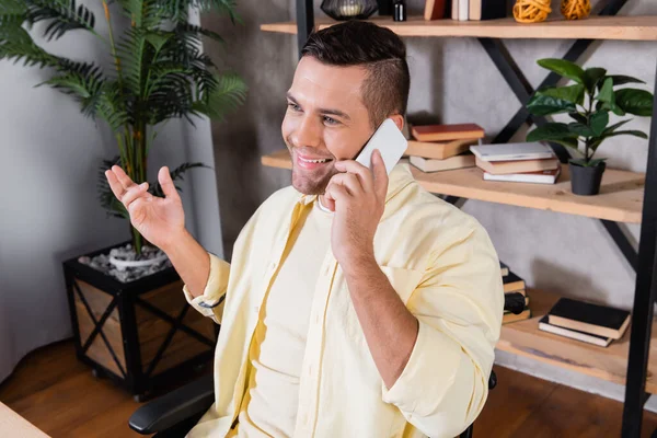 Sonriente Hombre Gesto Mientras Habla Teléfono Inteligente Casa — Foto de Stock
