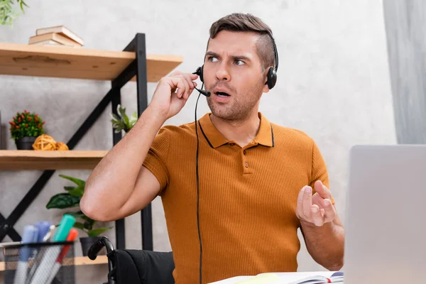 handicapped man in headset gesturing while working at home