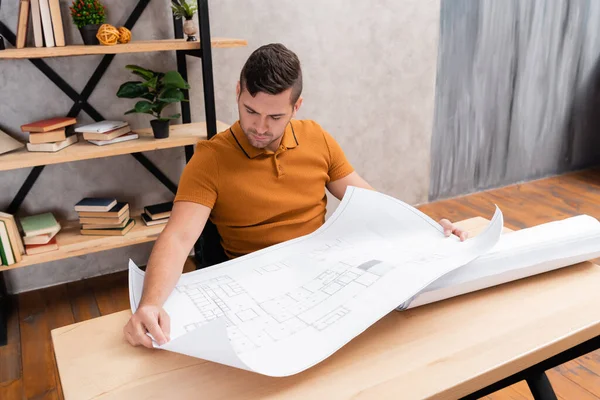 家で仕事をしながら設計図を見るフリーランスの建築家 — ストック写真