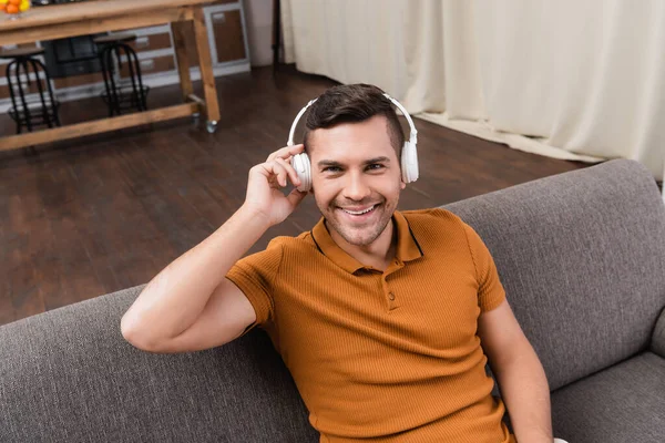 high angle view of happy man looking at camera while listening music in headphones