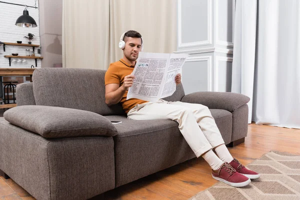 Homme Dans Les Écouteurs Écouter Musique Lire Journal Sur Canapé — Photo