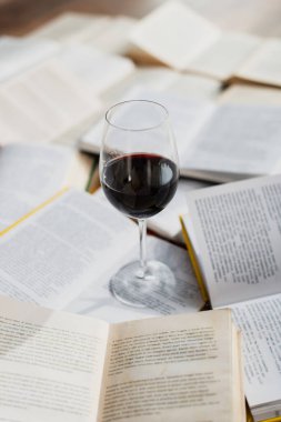 Kitap yığınının üzerinde bir kadeh kırmızı şarap. 
