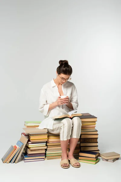 Comprimento Total Jovem Mulher Óculos Sentado Pilha Livros Enquanto Lendo — Fotografia de Stock