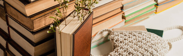 полевые цветы рядом с грудой книг в твёрдом переплете и вязаным мешком для перекрещивания на белом, баннер