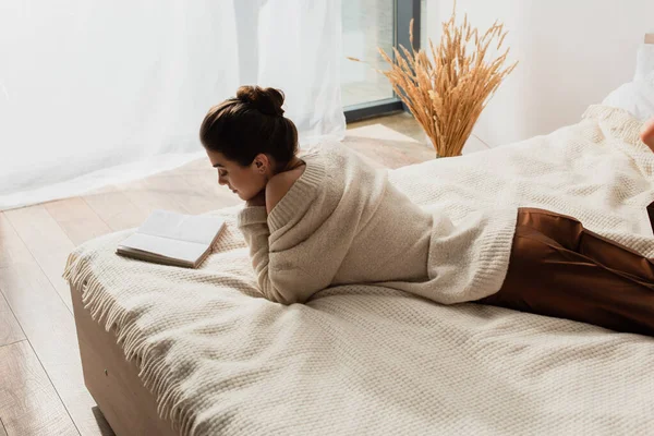 Νεαρή Γυναίκα Διαβάζει Βιβλίο Ενώ Αναπαύεται Στο Κρεβάτι — Φωτογραφία Αρχείου
