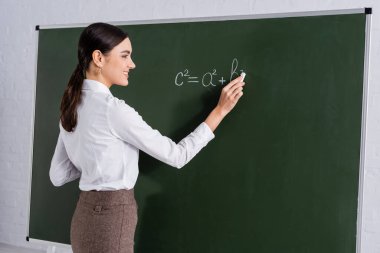 Gülen öğretmen tahtaya matematiksel denklem yazıyor. 