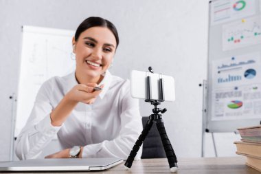 Selfie çubuğundaki akıllı telefon video görüşmesi sırasında eliyle işaret eden bulanık iş kadınının yanında. 